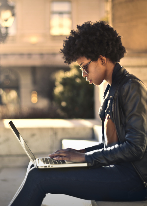 Gifty typing on laptop outside